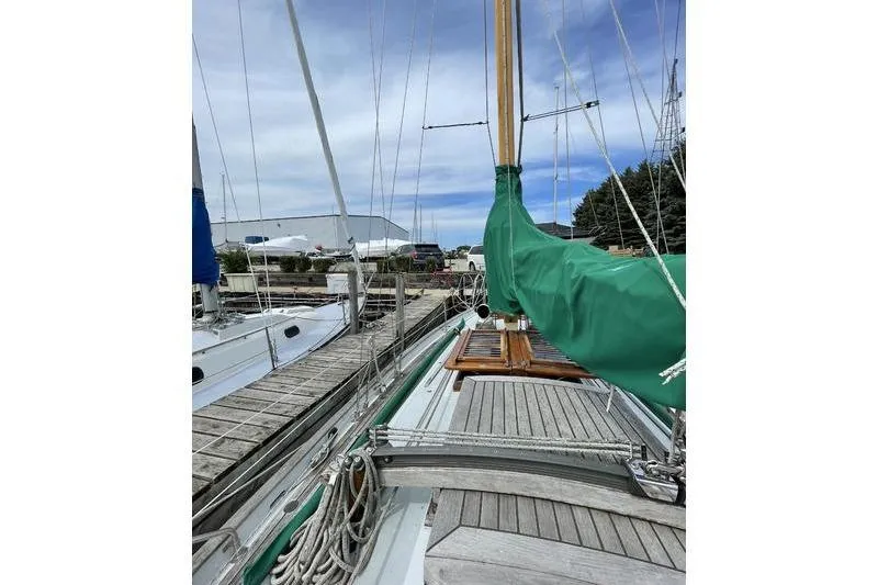 Slide: The Image of 1980 Ta Shing Baba 30 sailboat docked, featuring wooden deck and green sail cover. - 4