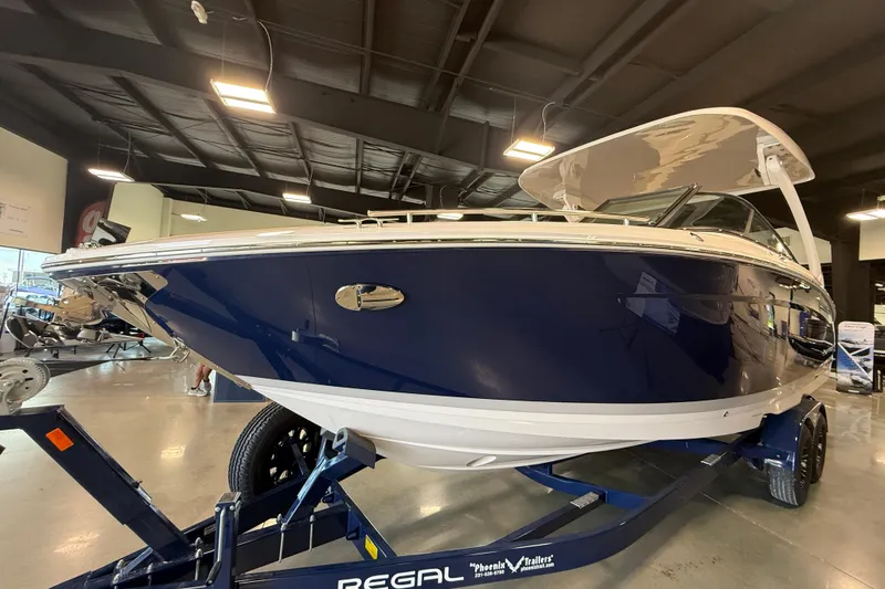 Slide: The Image of 2027 Regal LS9 boat in showroom, sleek blue and white design on trailer. - 2