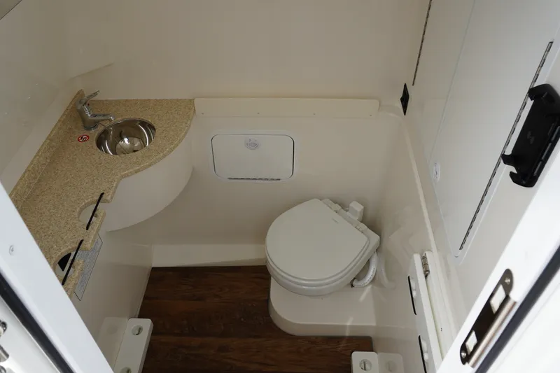 Slide: The Image of 2027 Regulator 31 boat bathroom with sink, toilet, and wooden flooring. - 18