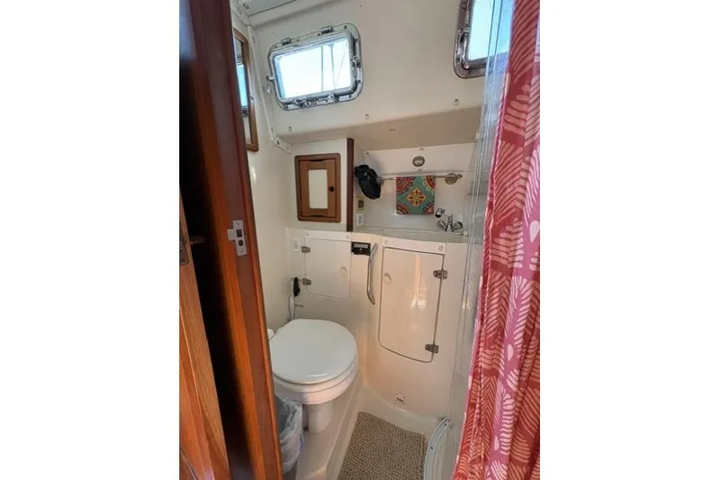 Slide: The Image of Compact bathroom in 2002 Saga 43 boat with toilet, sink, and colorful shower curtain. - 34