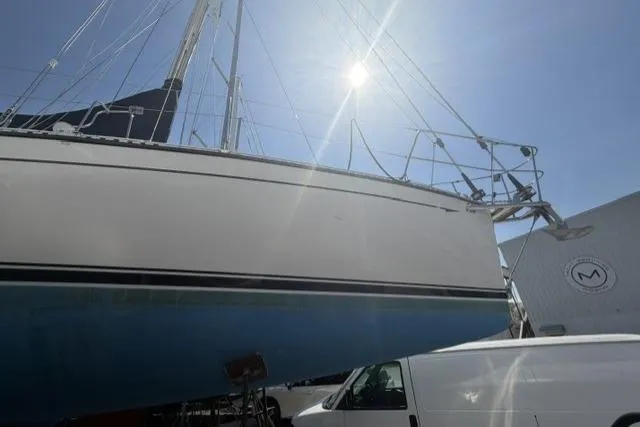Slide: The Image of Sailboat Saga 43, 2002 model, docked under bright sun with a van nearby. - 38