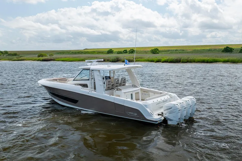 Slide: The Image of 2017 Boston Whaler 420 Outrage boat on a serene waterway under a cloudy sky. - 3