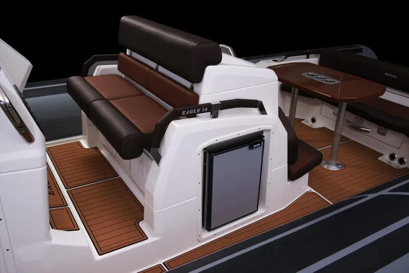 Slide: The Image of 2027 Brig Eagle 10 boat interior with brown seating and wooden flooring. - 10