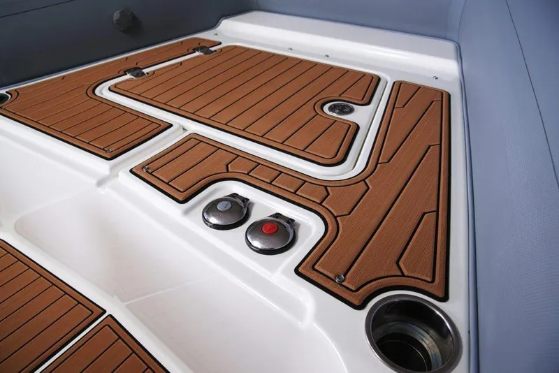 Slide: The Image of 2027 Brig Eagle 10 boat deck with brown non-slip flooring and control buttons. - 8