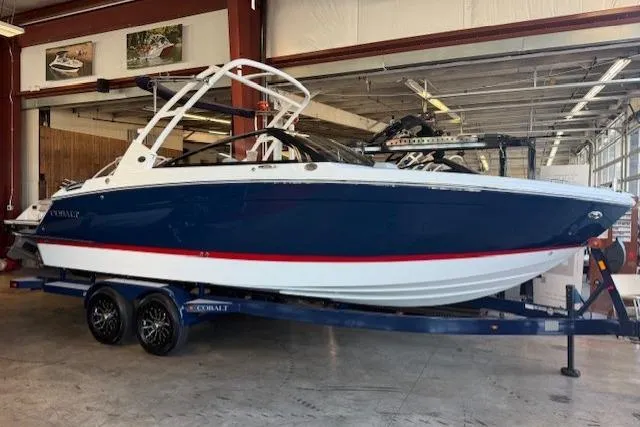 The Image of 2026 Cobalt R6 boat in showroom, blue and white design on trailer. - 1