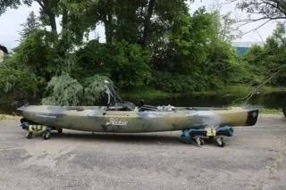 Slide: The Image of 2023 Hobie Mirage Compass kayak on wheeled stands, surrounded by lush greenery. - 2