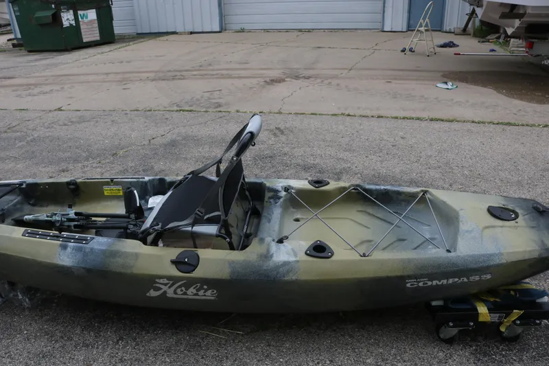 The Image of 2023 Hobie Mirage Compass kayak on pavement, featuring adjustable seat and storage area. - 0