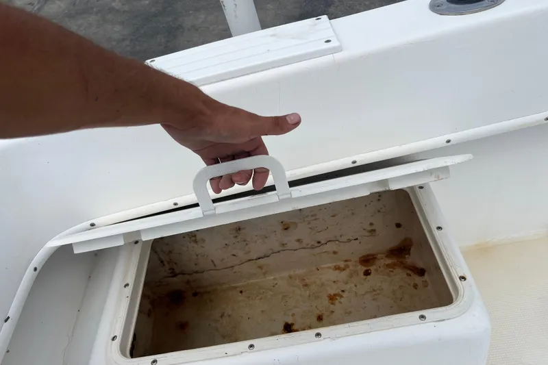 Slide: The Image of Hand opening storage compartment on 2007 Duskey 256 boat, revealing interior stains. - 21