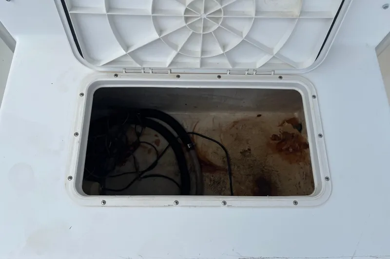 Slide: The Image of Open storage compartment on a Duskey 256 boat, showing cables and rust stains. - 13