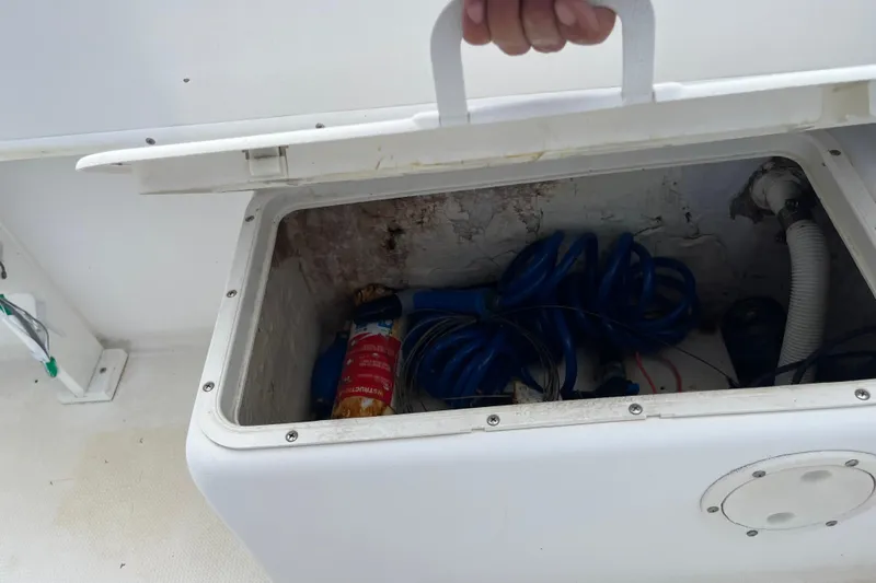 Slide: The Image of Open storage compartment on a Duskey 256 boat, containing coiled blue hose and fire extinguisher. - 19