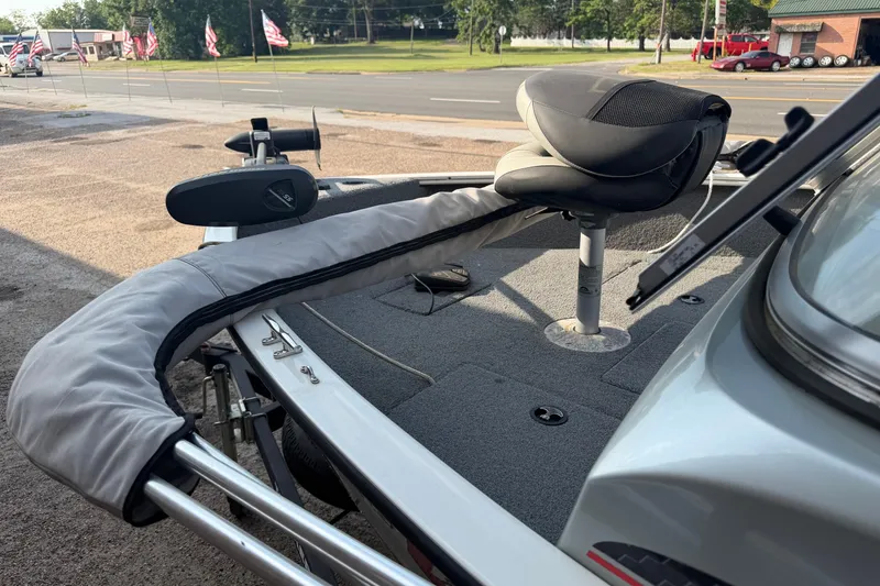Slide: The Image of 2018 Tracker Pro Guide V-165 WT boat with cushioned seating and trolling motor, parked roadside. - 5