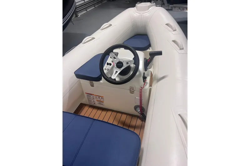 Slide: The Image of 2026 Brig Falcon 360 inflatable boat interior with steering wheel and blue seating. - 3