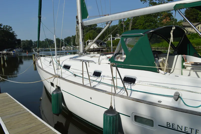 Slide: The Image of 1999 Beneteau 411 sailboat docked, featuring green canopy and sleek white hull. - 3