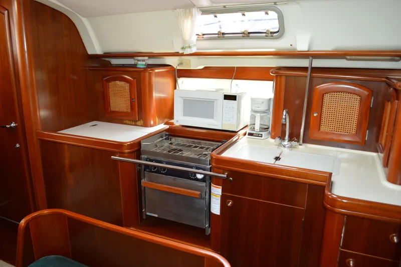 Slide: The Image of Interior of a 1999 Beneteau 411 yacht kitchen with wood cabinetry and modern appliances. - 28