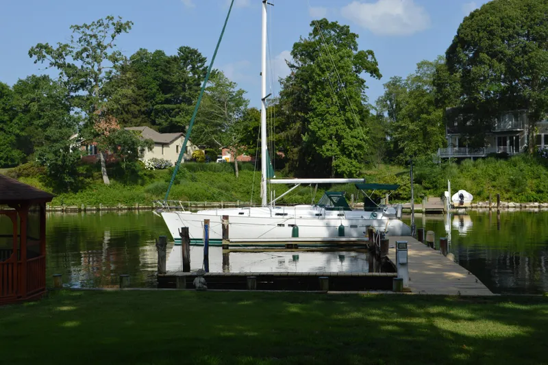 Slide: The Image of Sailboat Beneteau 411 (1999) docked on a serene lake with lush greenery. - 1