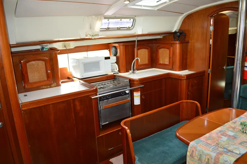Slide: The Image of Interior of a 1999 Beneteau 411 yacht featuring a well-equipped kitchen area. - 27