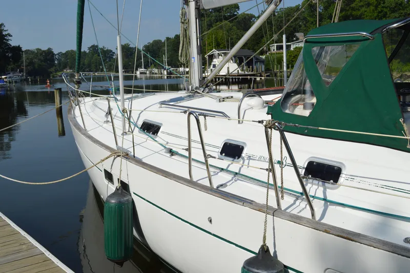 Slide: The Image of Sailboat Beneteau 411, 1999 model, docked at a serene marina with green canopy. - 2