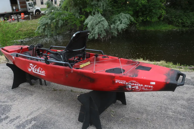 Slide: The Image of Red 2023 Hobie Mirage Pro Angler 14 kayak displayed near a pond. - 6