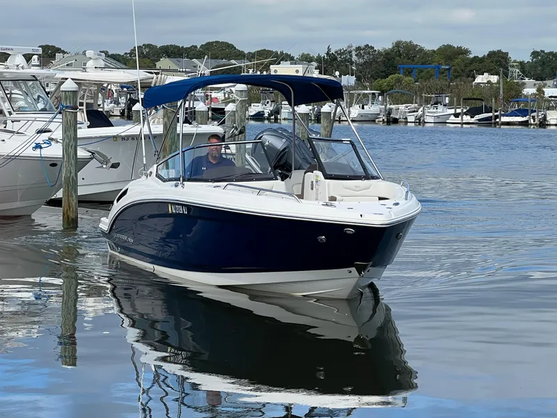 Slide: The Image of A 2016 Chaparral 257 SSX boat is docked on the water. It features a blue canopy. - 12
