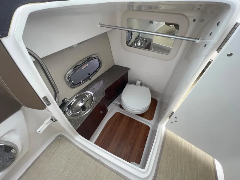 Slide: The Image of Interior view of a boat bathroom with toilet, sink, and mirror. Wood flooring and window present. - 36