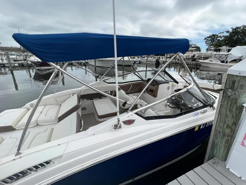Slide: The Image of A 2016 Chaparral 257 SSX boat with a blue canopy, docked at a marina. - 20