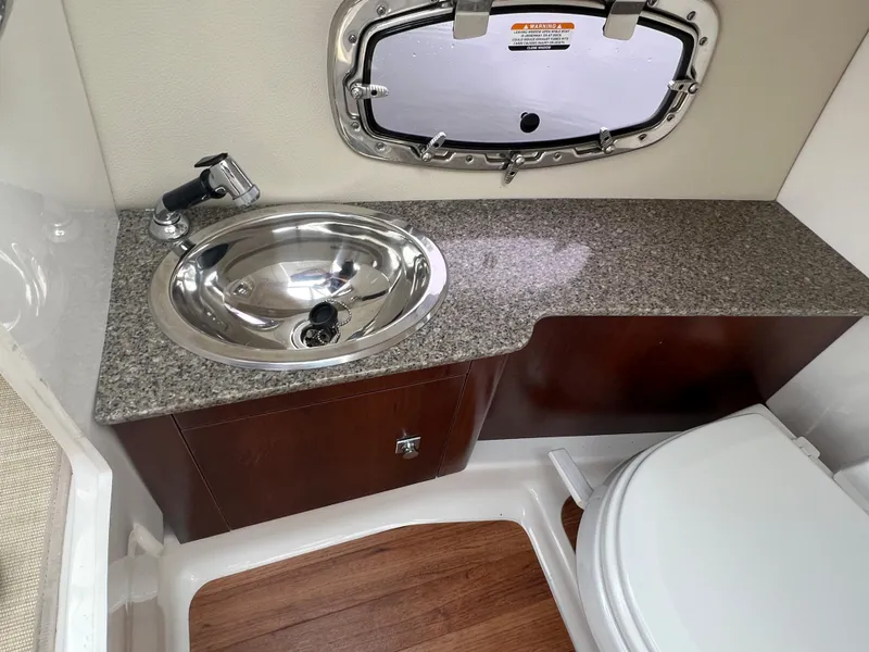 Slide: The Image of Interior of a 2016 Chaparral 257 SSX with a sink, toilet, and wood accents. - 38