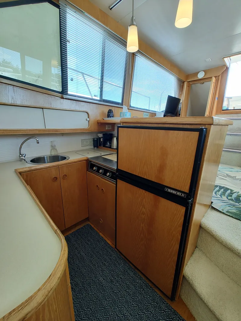Slide: The Image of The galley of a 1989 Chris-Craft 372 Catalina with wooden cabinets, sink, and refrigerator. - 49