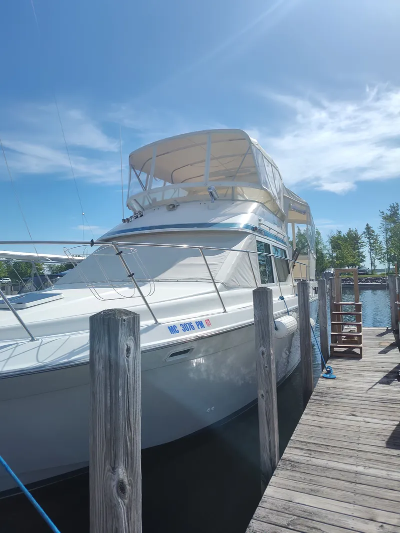 Slide: The Image of A 1989 Chris-Craft 372 Catalina docked at a wooden pier. It features a large canopy and sleek lines. - 32