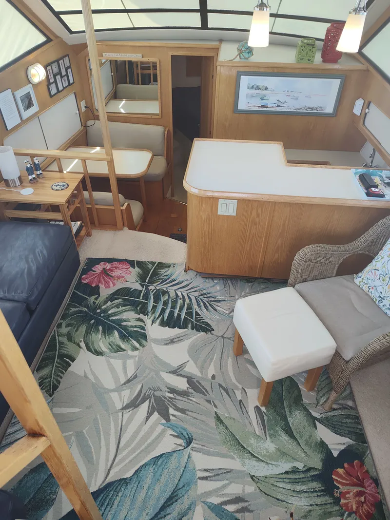 Slide: The Image of Interior of a 1989 Chris-Craft Catalina with cozy seating and a tropical-themed rug. - 9