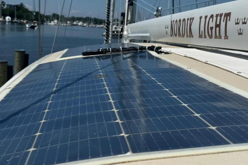 Slide: The Image of Solar panels on a 1989 Mason 54 sailboat named "Nordik Light" docked at a marina. - 54