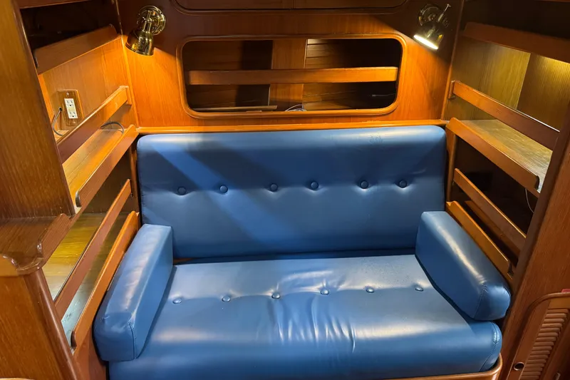 Slide: The Image of Blue leather sofa in a 1989 Mason 54 yacht interior with wooden shelves and lighting. - 9