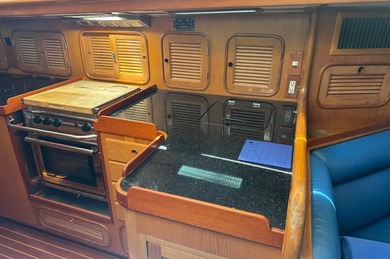 Slide: The Image of 1989 Mason 54 yacht kitchen with wooden cabinets, stove, and black countertop. - 14