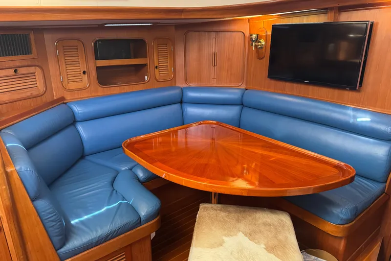 Slide: The Image of Luxurious 1989 Mason 54 yacht interior with blue leather seating, wooden table, and mounted TV. - 11