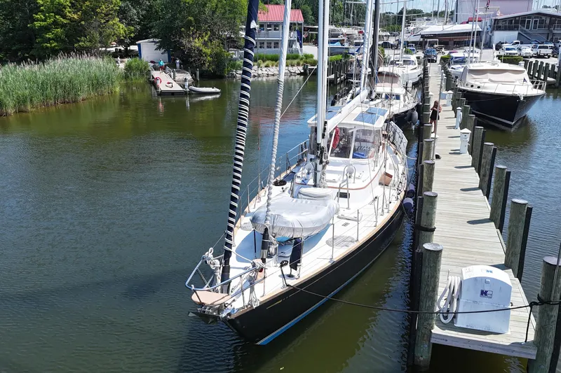 Slide: The Image of Sailboat docked at marina, Mason 54 model, 1989, surrounded by calm water and greenery. - 60