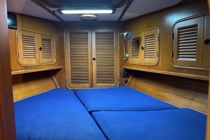Slide: The Image of Cozy cabin interior of 1989 Mason 54 yacht with blue cushions and wooden paneling. - 4