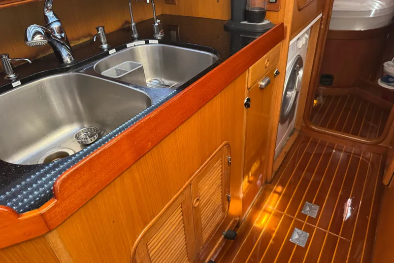 Slide: The Image of Wooden yacht kitchen with dual sinks, washing machine, and polished flooring, Mason 54, 1989 model. - 17