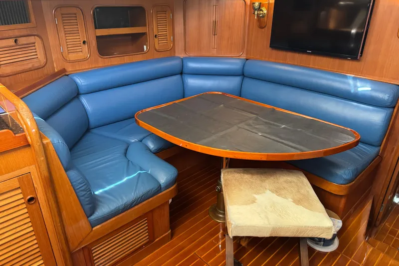 Slide: The Image of Cozy 1989 Mason 54 yacht interior with blue seating and wooden table. - 1