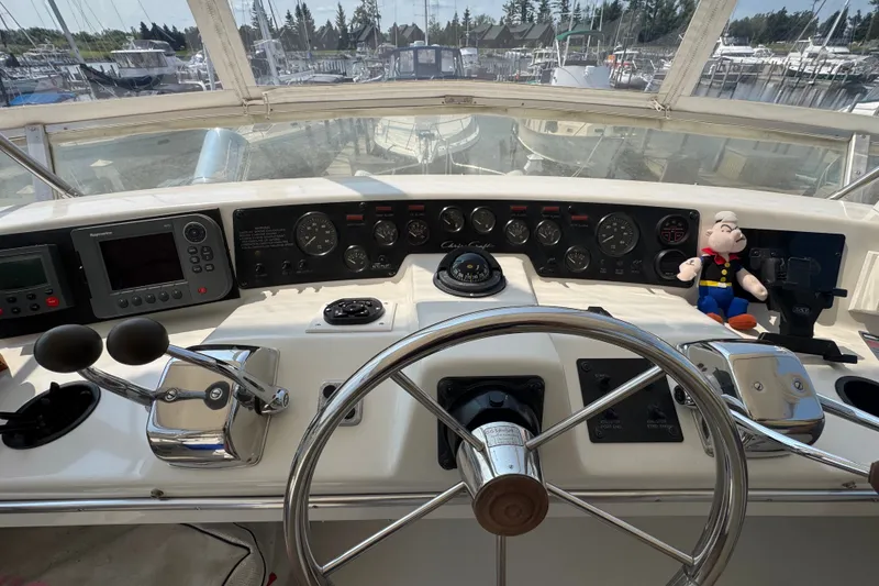 Slide: The Image of 1989 Chris-Craft 372 Catalina helm with controls, gauges, and plush toy on dashboard. - 35