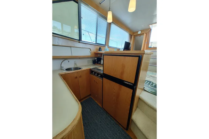 Slide: The Image of 1989 Chris-Craft 372 Catalina yacht interior with kitchenette, featuring wood cabinetry and modern appliances. - 12