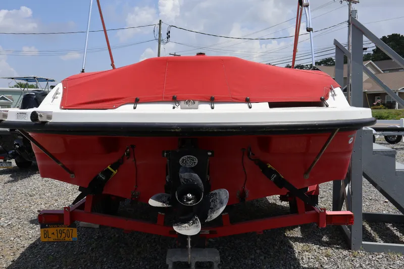 Slide: The Image of 2008 Starcraft 2000 IO Limited boat with red cover, parked on gravel. - 13