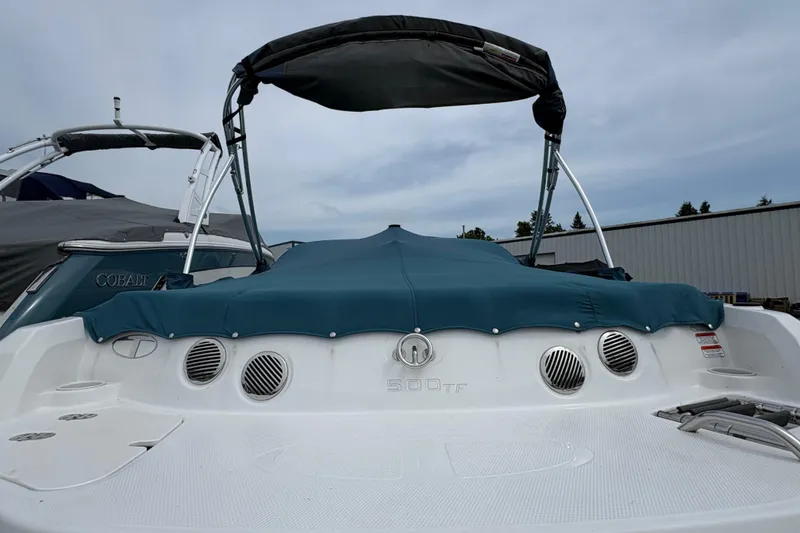 Slide: The Image of 2018 Tahoe 500 TF boat with blue cover and canopy, docked outdoors. - 2