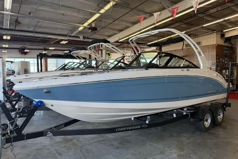 Slide: The Image of 2026 Chaparral 23 SSi boat in showroom, blue and white design on trailer. - 3