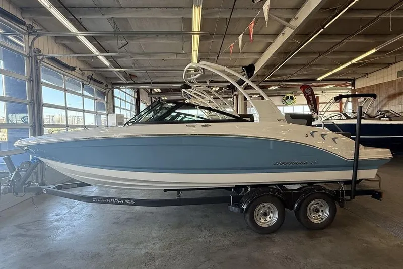 The Image of 2026 Chaparral 23 SSi boat in showroom, blue and white design on trailer. - 1