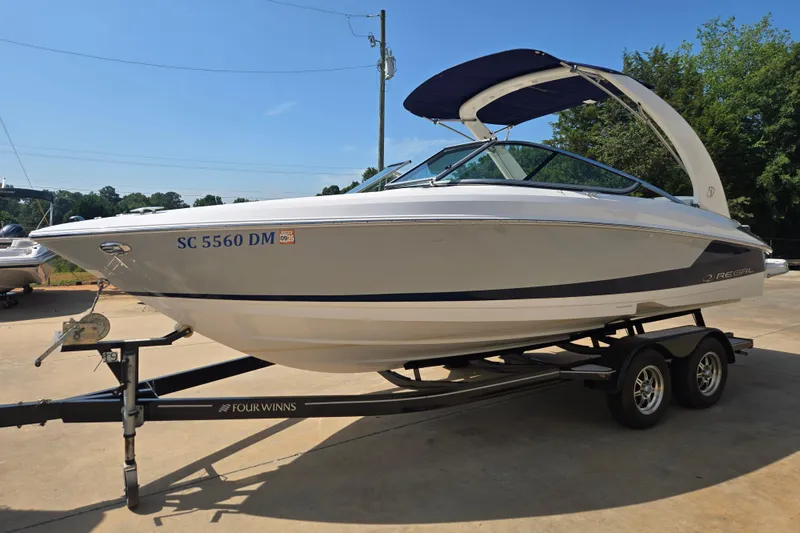 Slide: The Image of 2020 Regal 2300 Bowrider boat on trailer, parked outdoors under clear sky. - 2