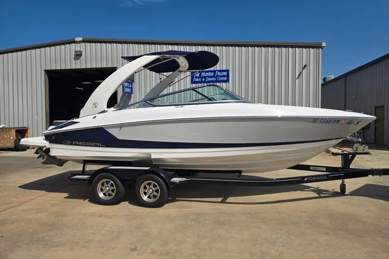 The Image of 2020 Regal 2300 Bowrider boat on trailer, parked outside a service center. - 0