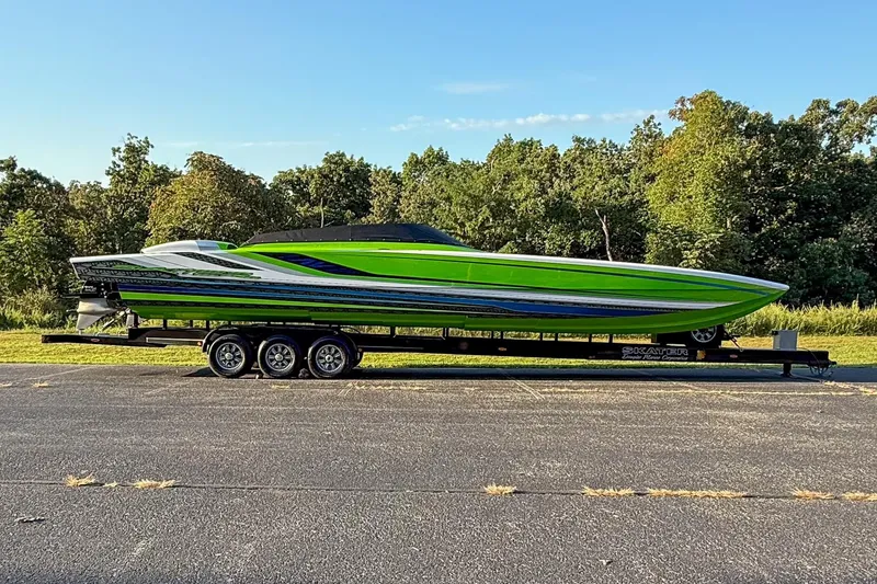 Slide: The Image of Green Skater 388 speedboat on trailer, 2025 model, parked outdoors with trees in background. - 19