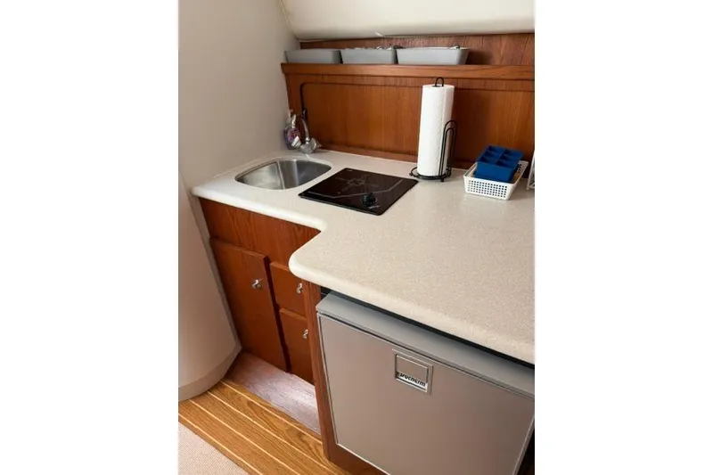 Slide: The Image of Compact kitchen area in a 2002 Tiara 29 boat with sink, stove, and fridge. - 11
