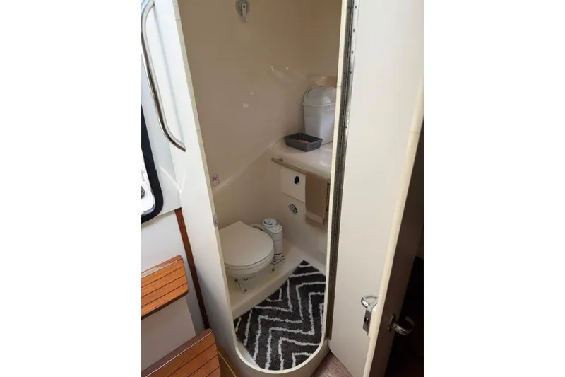 Slide: The Image of Compact bathroom in a 2002 Tiara 29 boat, featuring a toilet and storage space. - 9