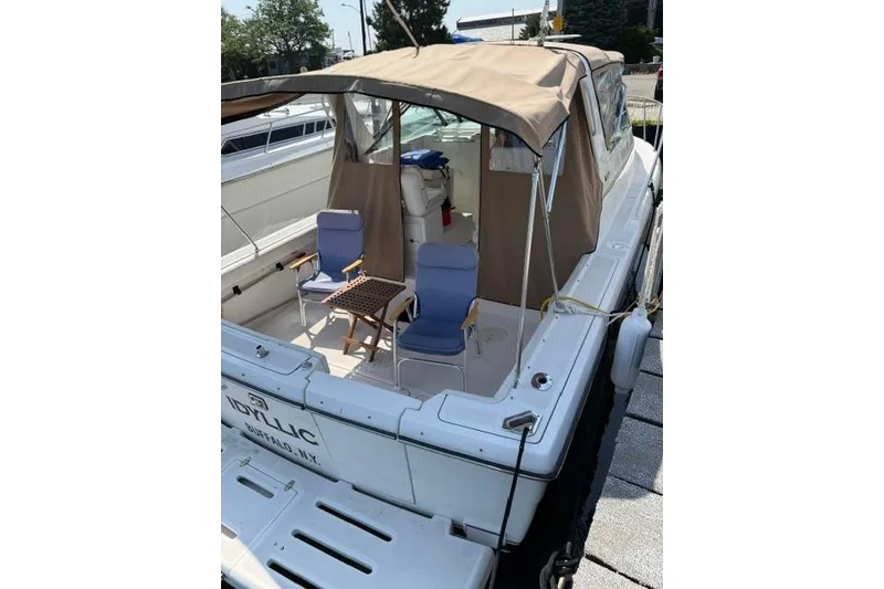 Slide: The Image of 2002 Tiara 29 boat with canopy, docked, featuring two blue chairs on deck. - 19