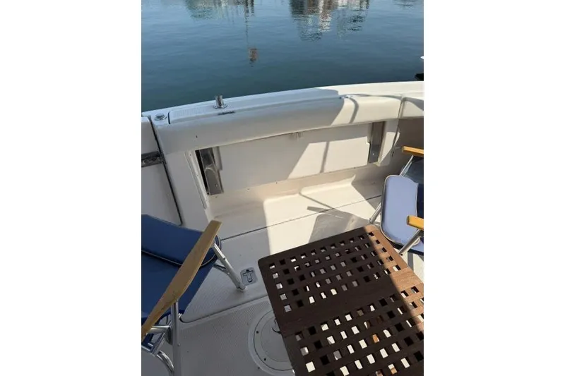 Slide: The Image of 2002 Tiara 29 boat deck with chairs and table, overlooking calm water. - 18
